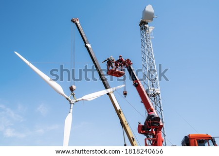 Construction of a wind power plant. Installers use a truck crane and aerial platform to raise the wind turbine rotor. Photo taken on a sunny summer day in Russia Royalty-Free Stock Photo #1818240656