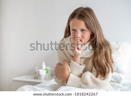 a girl with a temperature sits on the bed and coughs Royalty-Free Stock Photo #1818242267