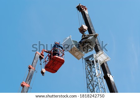 Workers on the aerial platform with the help of a crane carry out the installation of the wind generator. Russia, Orenburg region Royalty-Free Stock Photo #1818242750