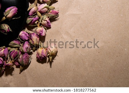 Black plate with Tea made from dried buds and petals of a purple damask rose on a paper background in the upper left corner