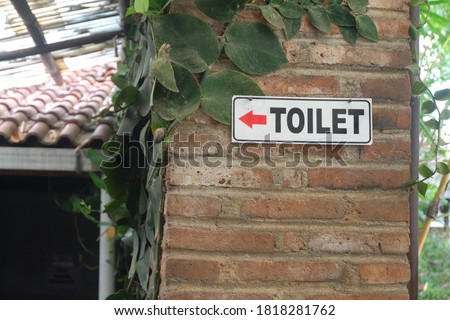 Wooden toilet sign on the brick wall