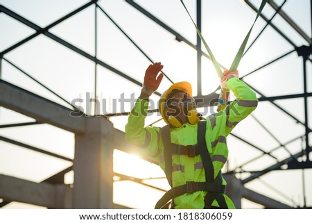 Asian construction worker Wear safety clothing and harnesses to do construction work on steel roof structures.