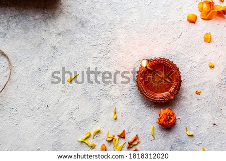 Diwali Diyas and sweet or mithai on a white rustic wall background with flowers and earthen lamps Royalty-Free Stock Photo #1818312020