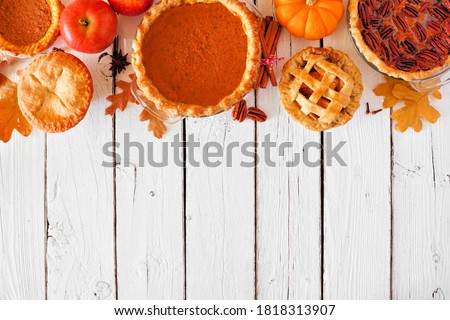 Mixed homemade autumn pies. Pumpkin, apple and pecan. Overhead view top border on a white wood background with copy space.