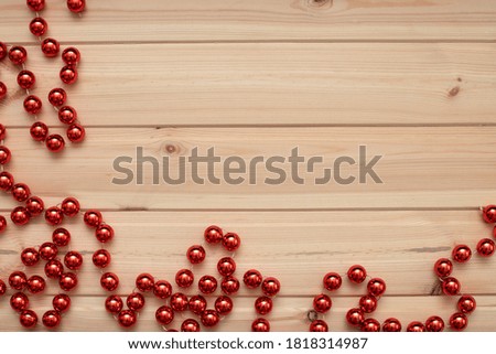 Christmas card. Red Christmas tree beads adorn the edges of the light wooden background. Flat bed, top view, copy space. Christmas frame.