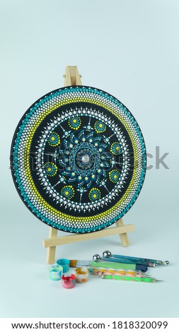 Beautiful Multi coloured mandala painting on a round canvas placed on a easel stand 