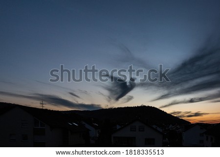 Dark cloud in shape of a pigeon in the evening sky Royalty-Free Stock Photo #1818335513