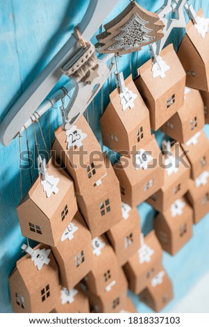 Creative Christmas Advent Calendar hanging on a clothes hanger on blue wooden background