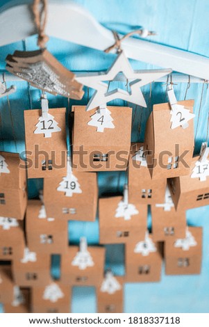 Handmade Christmas Advent Calendar made of cardboard and string on blue wooden background