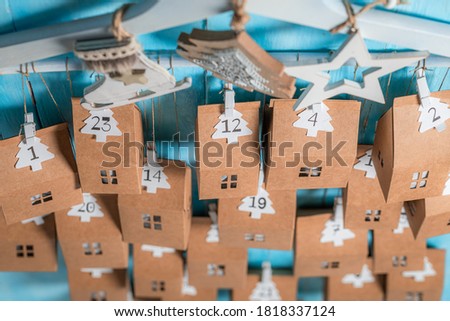 Unique Christmas Advent Calendar hanging on a clothes hanger on blue wooden background