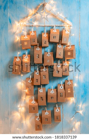 Creative Christmas Advent Calendar made of cardboard and string on blue wooden background