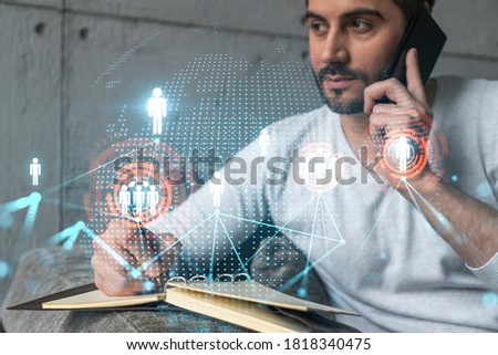 Handsome SMM manager in casual wears, speaking phone, taking notes at office try to determine customer needs to launch social media project. Double exposure. The concept of successful online business.