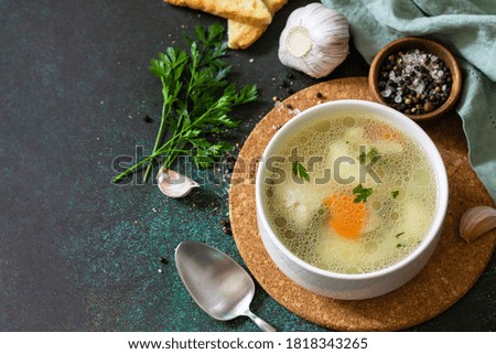 Chicken soup with vegetables on a dark stone table top. Copy space.