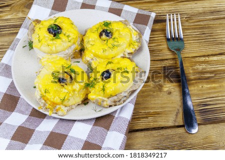 Pieces of baked pork with pineapple, cheese and olive on a wooden table