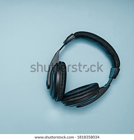 Large, black headphones lie on a colored background. Device for individual listening to music