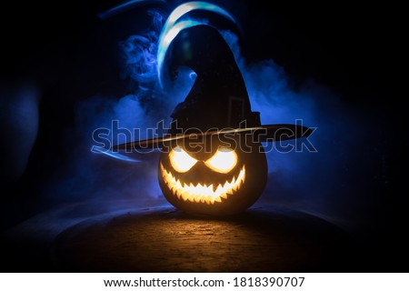 Halloween pumpkin smile and scary eyes for party night. Close up view of scary Halloween pumpkin with eyes glowing inside at black background. Selective focus