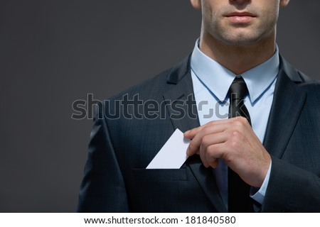 Part of body of man who pulls out business card from the pocket of business suit, copyspace