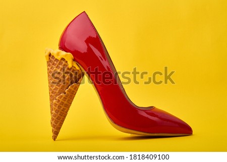Ice cream cone's used as a high heel. Original footwear design concept. Isolated on yellow background. Royalty-Free Stock Photo #1818409100