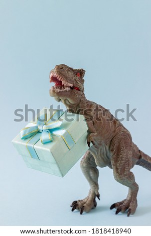 Dinosaur holds a gift box. Minimal concept. Idea