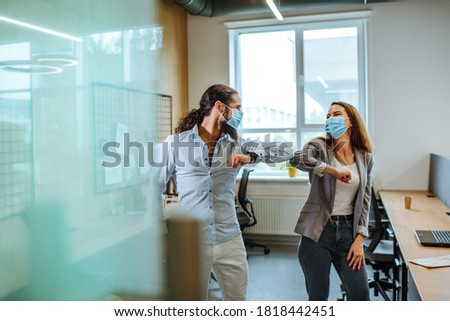 Informal greeting elbow bump by business people in the medical masks in the office during outbreak of the global pandemic COVID-19. Avoiding handshakes in a new normal. Royalty-Free Stock Photo #1818442451