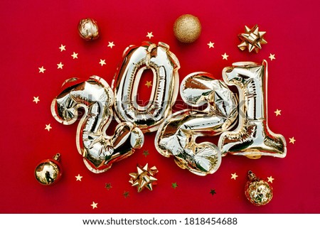 Banner. Happy New year 2021 celebration. Gold  foil balloons numeral 2021 and gold confetti on red background. Flat lay.