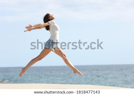 Full body profile of a happy woman with long waxed legs jumping on the beach Royalty-Free Stock Photo #1818477143