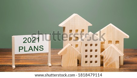 A poster with the words Plans 2021 and wooden houses. Real estate planning and financing concept. Housing market. Mortgage, loan, investment. Repairs and refinance home. Forecasts Royalty-Free Stock Photo #1818479114