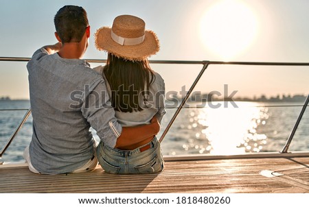 Couple in love sitting on yacht deck while sailing in the sea. Handsome man and beautiful woman having romantic date. Luxury travel concept. Royalty-Free Stock Photo #1818480260