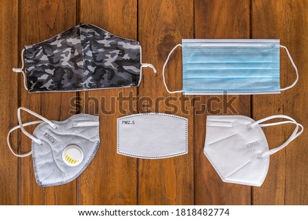 different kinds of face masks for protection against COVID-19,FPP2, KN95, FP2.5 filter, hygienic mask, surgical mask, and textile reusable face mask, on a wooden background top view Royalty-Free Stock Photo #1818482774