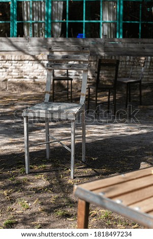 Old wooden chairs stand in an empty street cafe