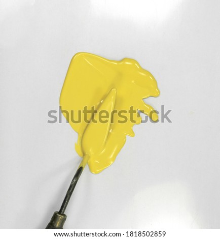 The puddle of yellow oil paint spill with a painter's scapula isolated over the white background. Paint Puddle Spill.