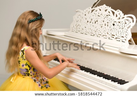The girl is at the white grand piano.