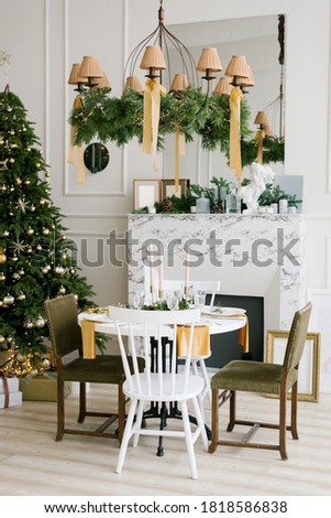 Stylish festive Christmas table with vintage chairs near the marble fireplace and Christmas tree in the living room or dining room in the house