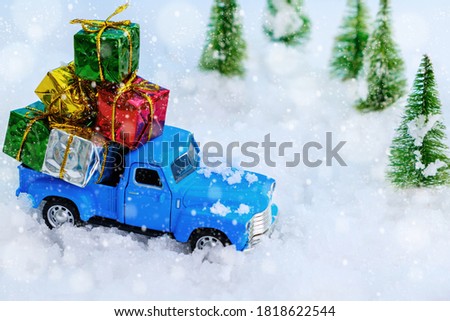 Vintage blue truck carrying many gifts through the snowy forest. Christmas and holiday concept