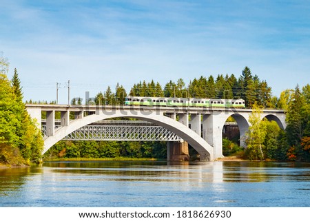 Autumn landscape of bridge with moving passenger train and Kymijoki river waters in Finland, Kouvola, Koria Royalty-Free Stock Photo #1818626930