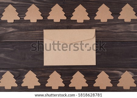Top above overhead view flat lay photo of christmas tree shaped paper decorations with craft envelope in center isolated on wooden background with copyspace
