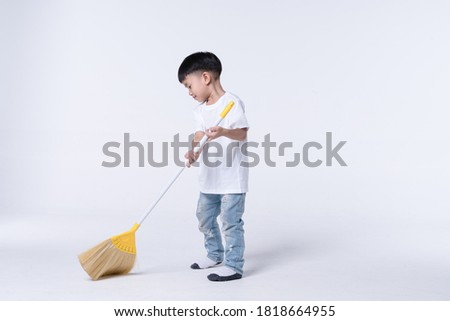 Asian boy about 4 year olds doing chore by sweep the house floor with plastic broom Royalty-Free Stock Photo #1818664955
