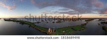 panoramic drone view of the green island with ancient wooden structures at sunrise