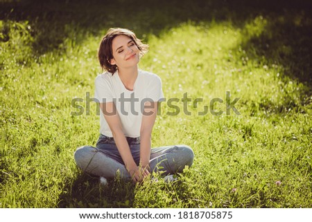 Photo of cute charming lady sitting lend ground fresh green grass enjoy sun rays eyes closed nature harmony student resting from city crowd people wear t-shirt jeans colorful park outdoors Royalty-Free Stock Photo #1818705875