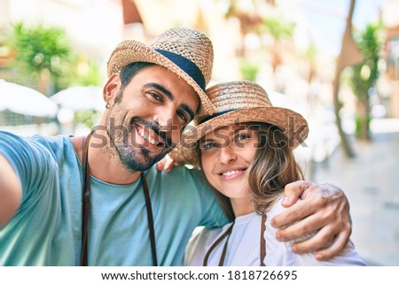Young couple of boyfriend and girlfriend tourists on a summer trip wearing summer hat taking a selfie picture