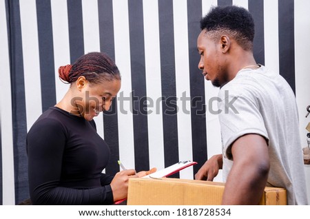 young black beautiful woman signing a manifest and taking a delivery from a delivery man