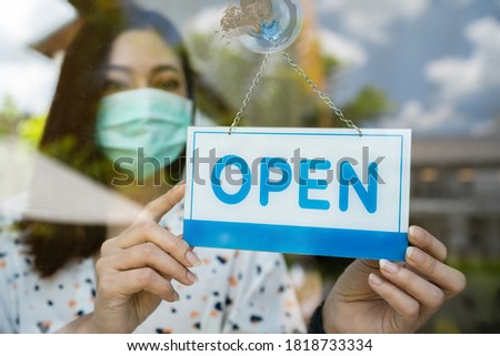 young woman owner with face mask open store after lockdown quarantine coronavirus (covid-19) pandemic