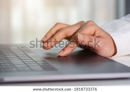 close-up female hand touching touchpad on a laptop computer Royalty-Free Stock Photo #1818733376
