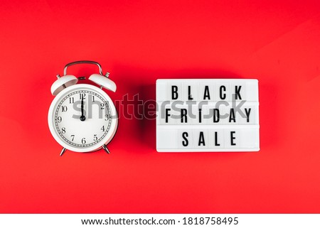 Black friday sale word on lightbox and alarm on red background table. Flat lay, top view