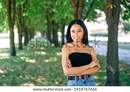 Smiling confident afro american woman with crossed arms posing outdoors. Relax, leisure, female beauty concept