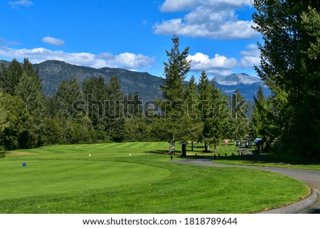 A picture of a golf course surrounded by beautiful mountains.   