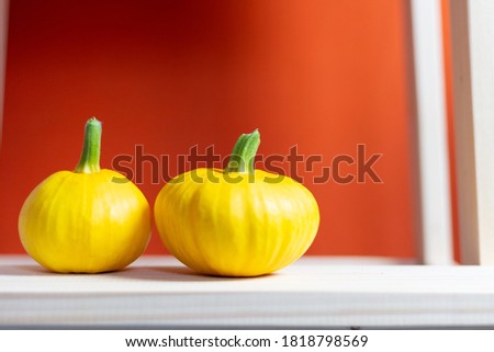 Two pumpkins on wooden table with orange background