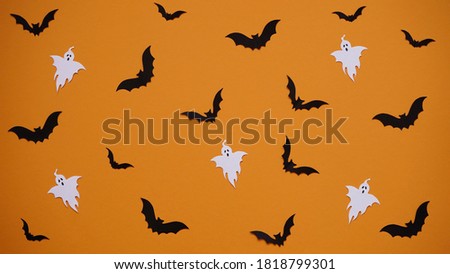 Halloween decoration concept - seamless pattern with black paper bats and ghosts on orange background, flat lay.Celebration of the dead.