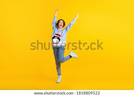 Full body photo of attractive lady x-mas party dance floor good mood greet friends raise hands arms wear penguin ugly ornament pullover jeans boots isolated yellow color background