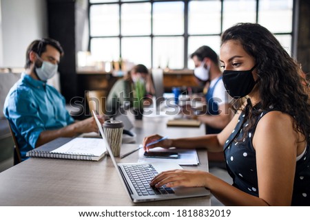 Business people with face masks indoors in office, back to work after coronavirus lockdown. Royalty-Free Stock Photo #1818832019